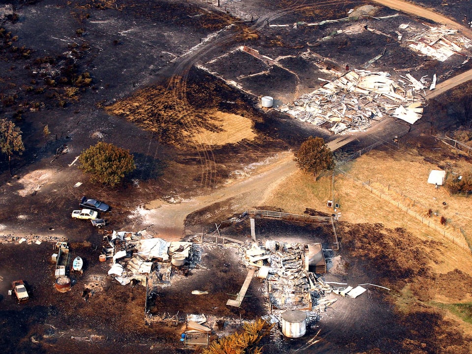 Verbrannte Landfläche und zerfallene Häuser in Dunalley, fotografiert aus einem Helikopter.