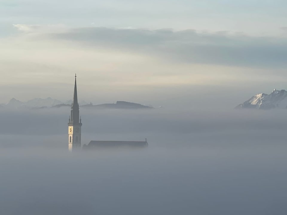 Kirchturm ragt aus dem Nebelmeer