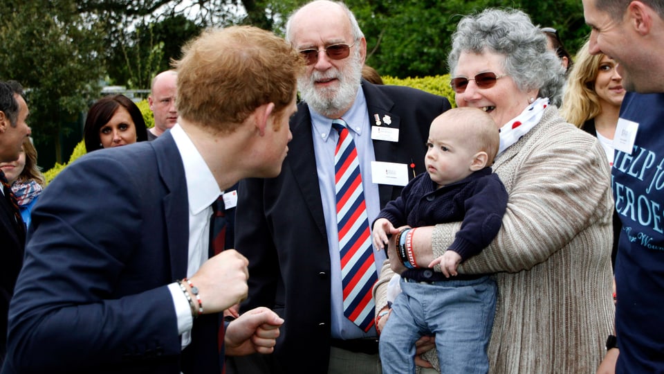 Bei der Eröffnung einer Rehaklinik für verletzte Soldaten im Südwesten Englands albert Prinz Harry mit einem Baby rum. Mai, 2013. 