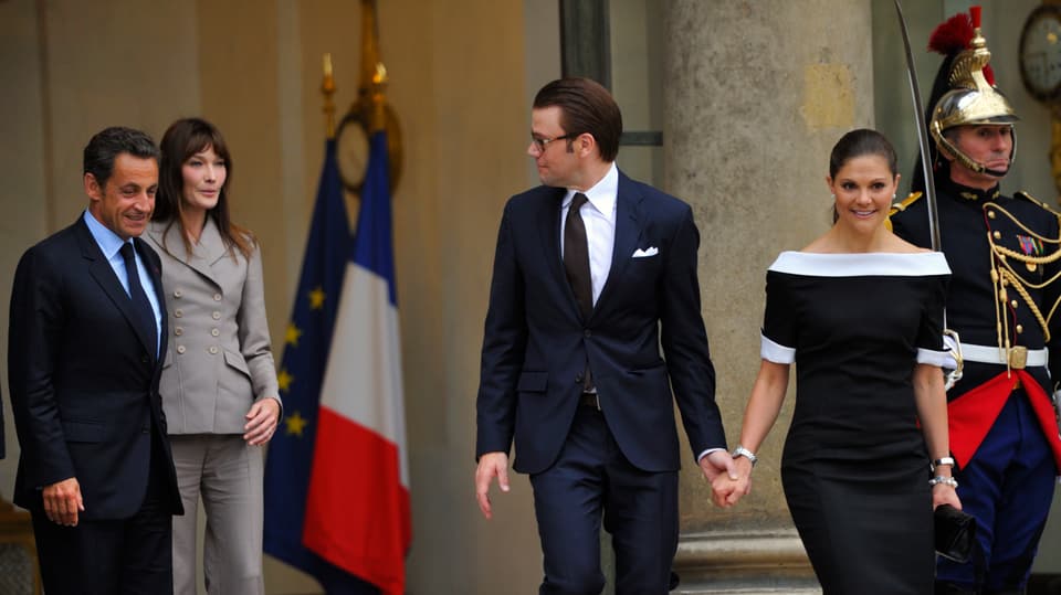 Daniel und Victoria halten Händchen. Neben ihnen stehen Carla Bruni und Nicolas Sarkozy.