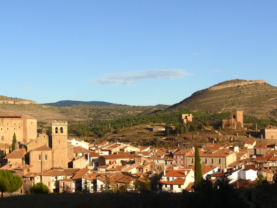 Eine Foto zeigt den spanischen Ort Mora de Rubielos: die Dächer leuchten rot, der Himmel ist blau.