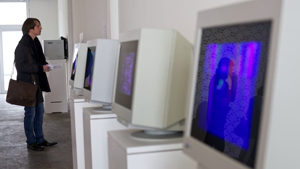 Ein Mann steht vor einer Reihe von Computerbildschirmen