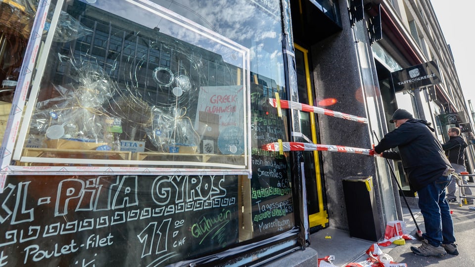 Ein Laden mit eingeschlagener Fensterscheibe, die Türe mit Polizei-Absperrband versperrt.