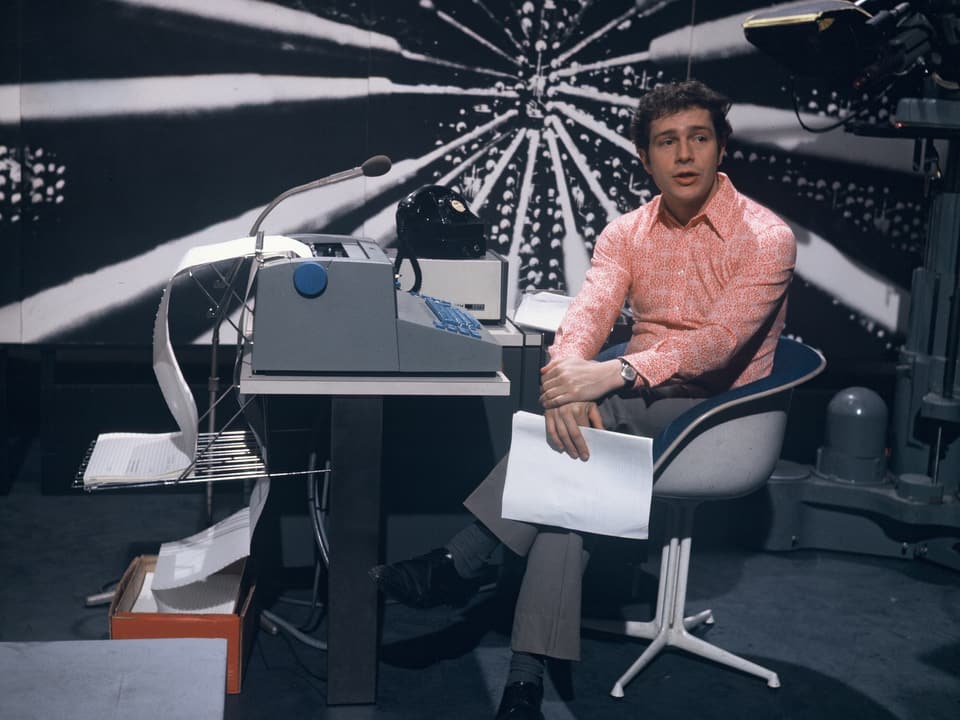Dieter Wiesmann sitzt in einem Studio auf einem Stuhl 