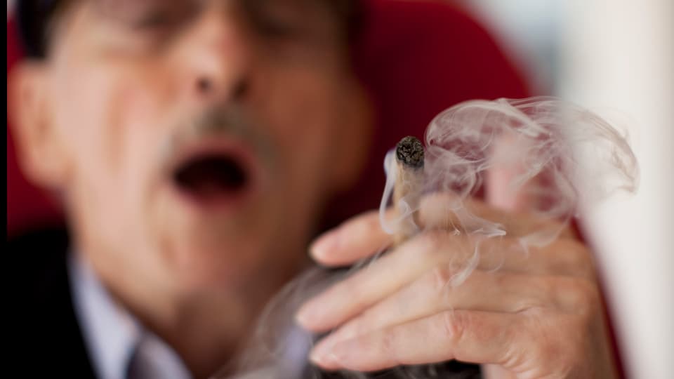 Ein älterer Mann raucht einen Joint.