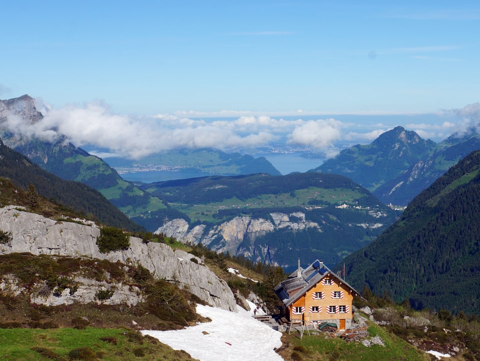 Alphütte mit toller Aussicht auf Berge, Seen, einige Wolken und den blauen Himmel. 