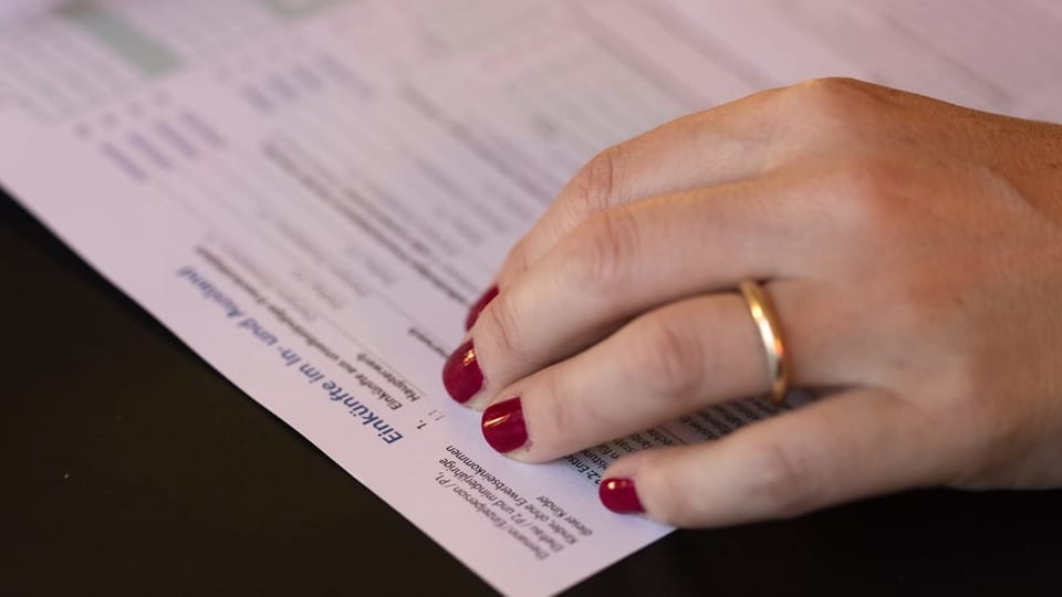 Eine Frau füllt eine Steuererklärung aus und trägt eineen Ehering.