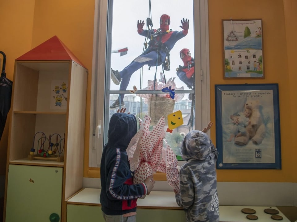 Männer in Spiderman-Kostümen verteilen Ostereier an Kinder auf einer Kinderstation in Mailand.