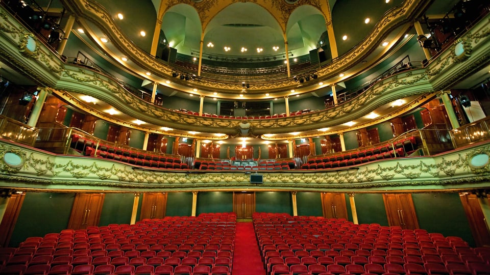 Farbaufnahme der Oper in Antwerpen innen mit roten Stühlen und grüner Decke