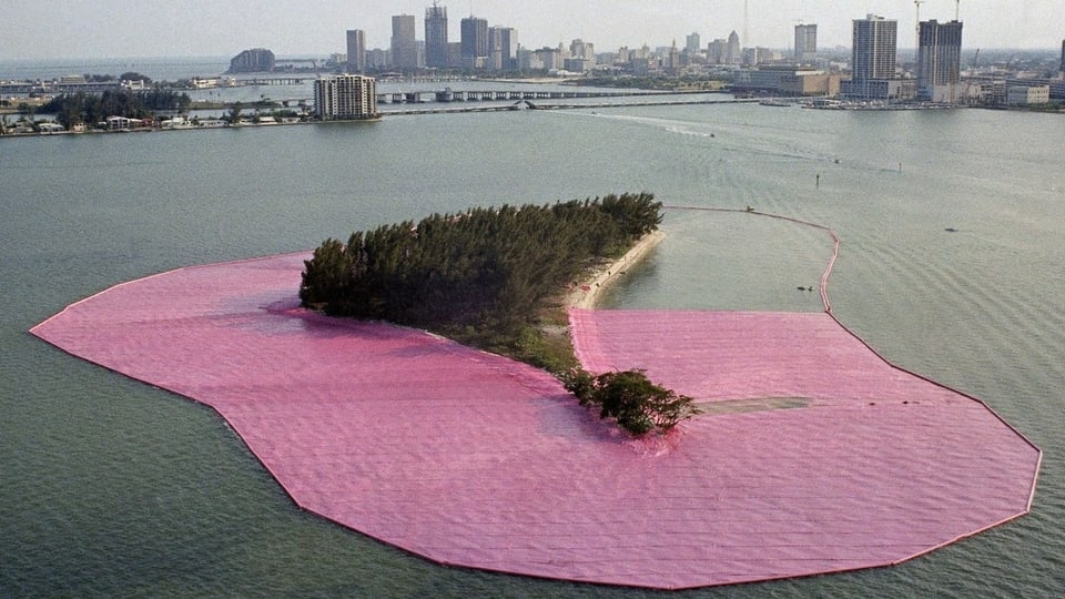 Eine Insel im offenen Meer vor den Toren einer Grossstadt, umgeben von einem rosafarbenen Band.