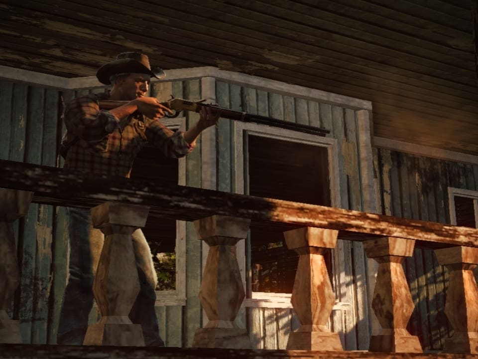 Ein Mann mit Gewehr zielt von einer Veranda aus.