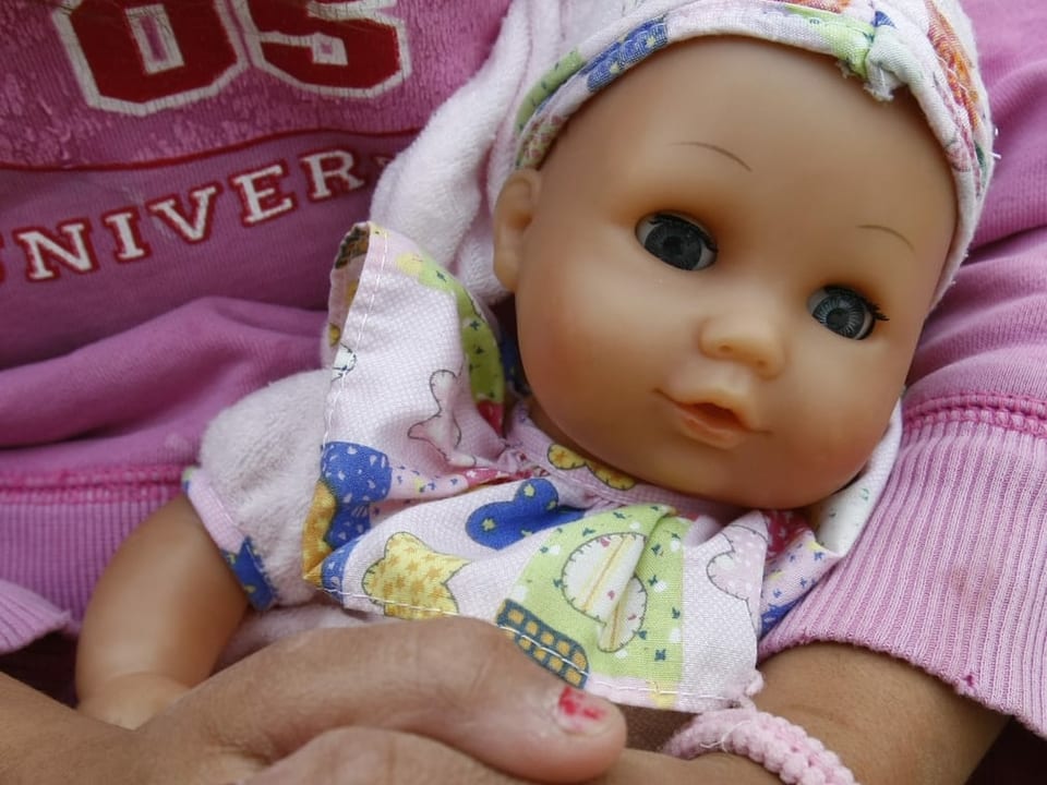 Ein Kind hält eine Puppe im Arm.