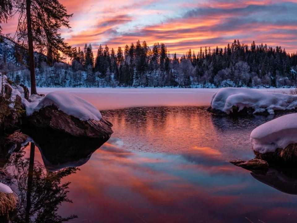 Morgenstimmung an einem verschneiten Bergsee mit Morgenrot und einigen Wolken.