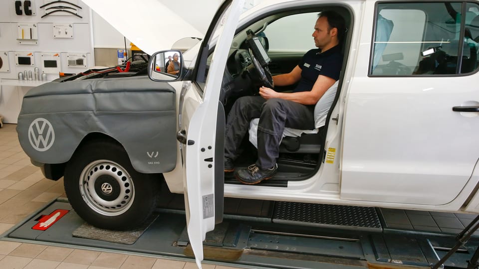 Ein VW auf dem Prüfstand mit offener Wagentür, im Inneren sitzt ein Techniker