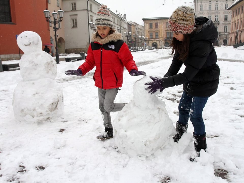 Kinder bauen Schneemänner