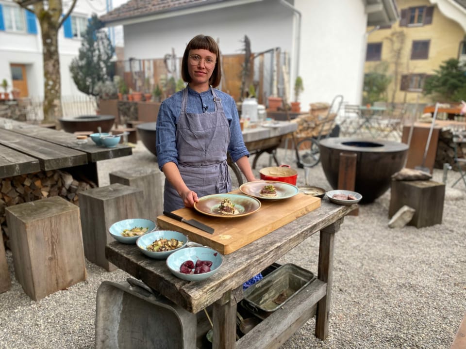 Eine Frau steht hinter einem Thresen.