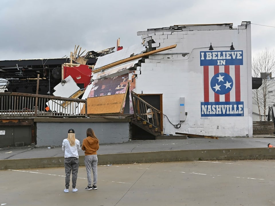 Zwei Frauen betrachten ein zerstörtes Gebäude