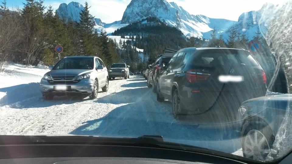Am rechten Strassenrand parkieren Autos, auf der schneebedeckten Strasse versuchen Autos, zu kreuzen.