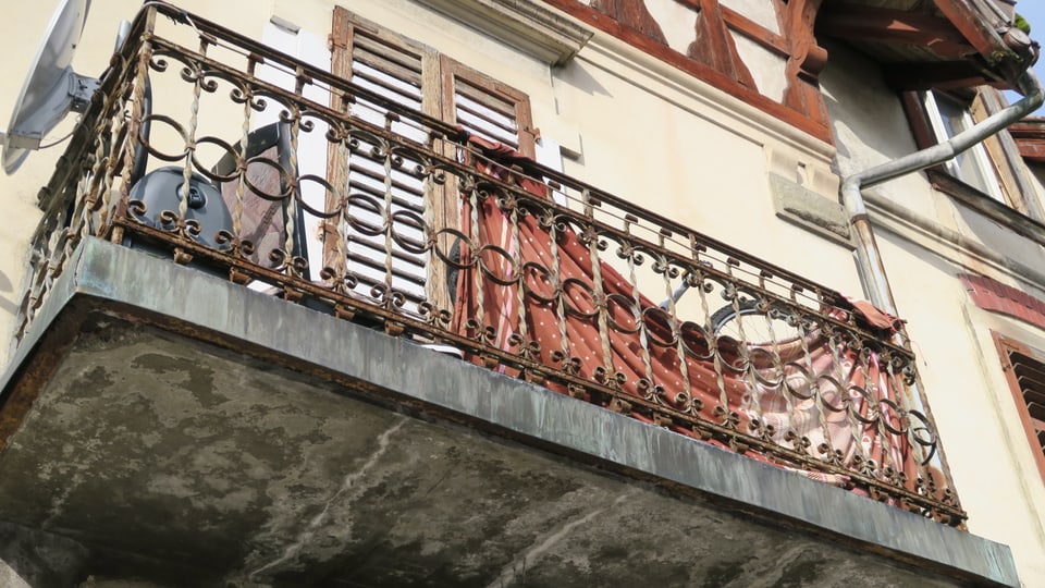 Ein in die Jahre gekommener Balkon mit Metallgeländer von unten fotografiert. 