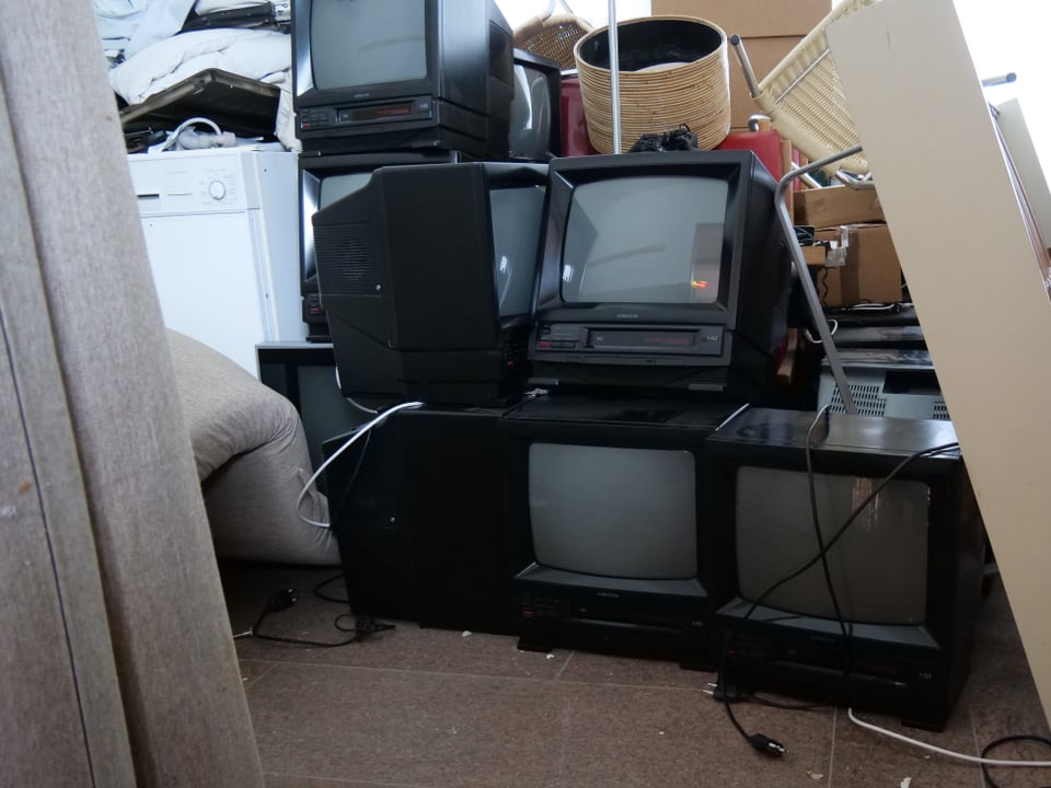 Fernseher, Kühlschrank, Lampen und Stühle in einer Kammer.