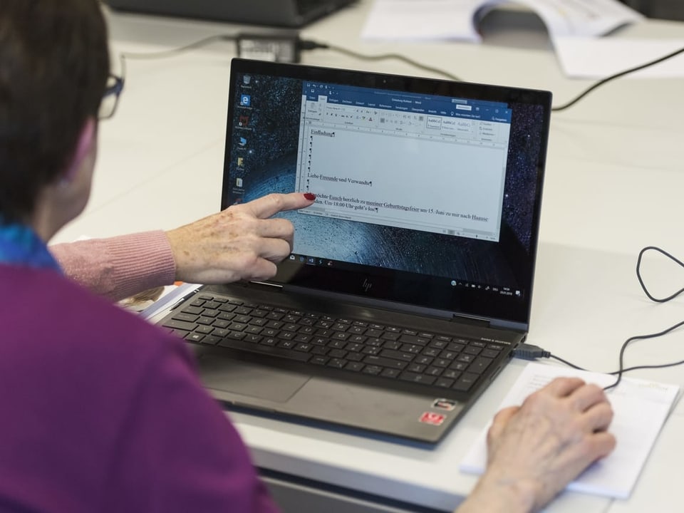 Blck über die Schultern einer Person, die einen Laptop bedient