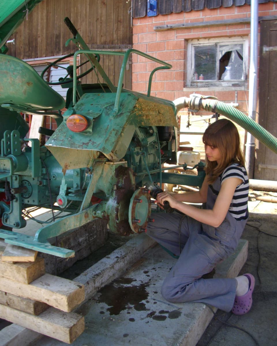 Eine Mädchen bei der Restaurierung eines Traktors.