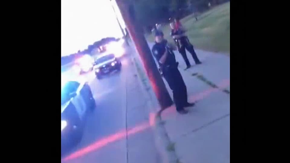 Bildschirmfoto einer Handy-Video-Szene mit einem Polizisten mit Pistole im Anschlag.