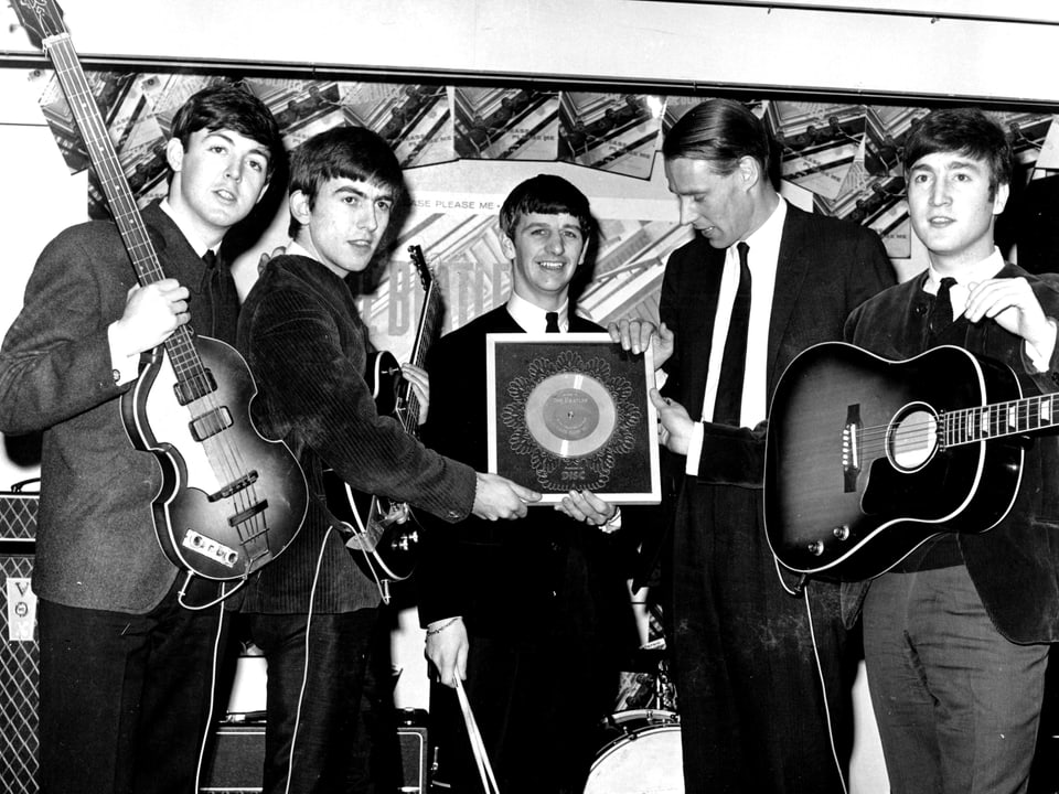 Die vier Beatles mit ihren Instrumenten, in ihrer Mitte George Martin, in der Hand eine Auszeichnung