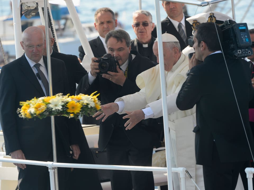 Der Papst wirft einen Blumenkranz von einem Schiff.