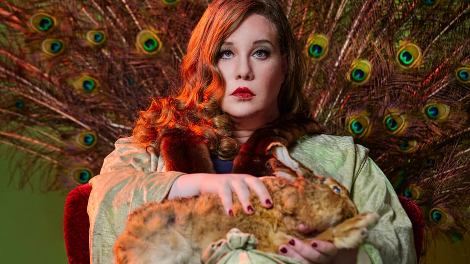 A woman with red hair holds a rabbit on her lap