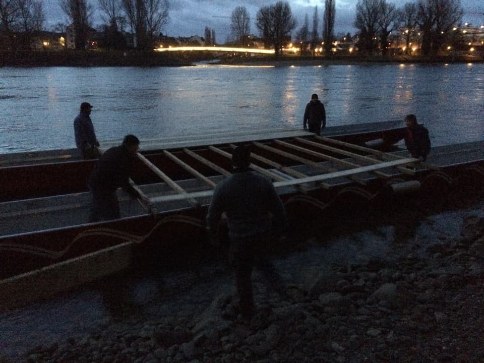Männer tragen Holzlatten auf ein Boot.
