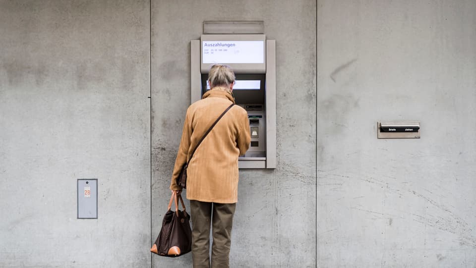 Eine Frau bezieht Geld an einem Bankomat.