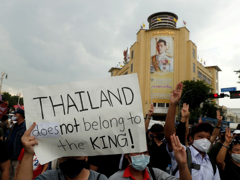 Menschenmasse und Plakat mit Aufschrift: Thailand does not belong to the king.