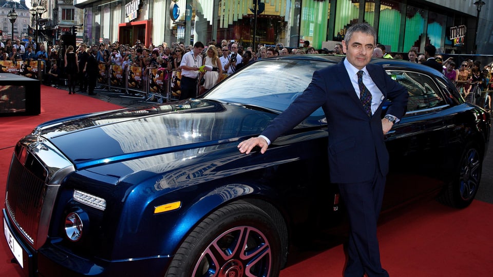 Rowan Atkinson posiert vor dem Rolls Royce.