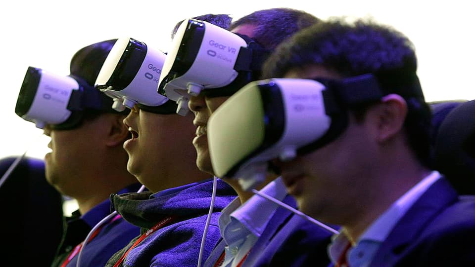 Testpersonen haben sich am «Mobile World Congress» in Barcelona eine VR-Brille von Samsung übergestreift. Sie leuchten ultraviolett.
