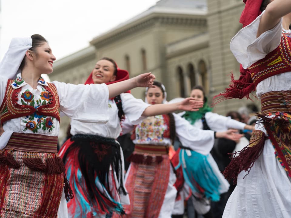 Eine Gruppe von Mädchen und jungen Frauen tanzt in bunten albanischen Folklore-Kostümen vor dem Bundeshaus.