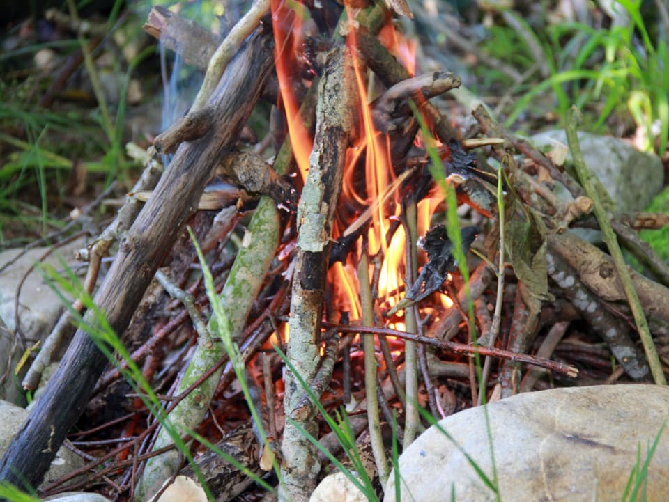 Ein paat Äste brennen, Steine um das Feuer.