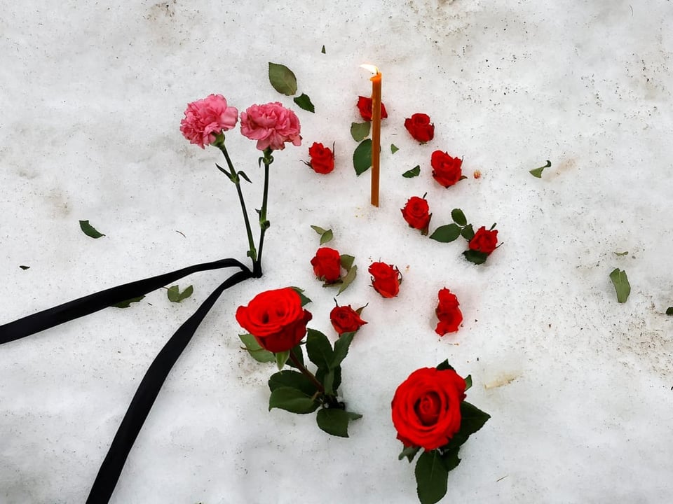 Rosen und Kerzen im Schnee.
