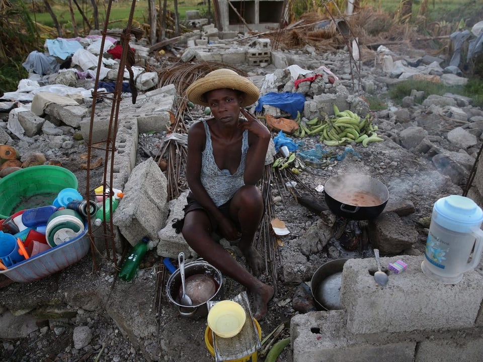 Eine Obdachlose vor Trümmern und ihrem Hab und Gut.
