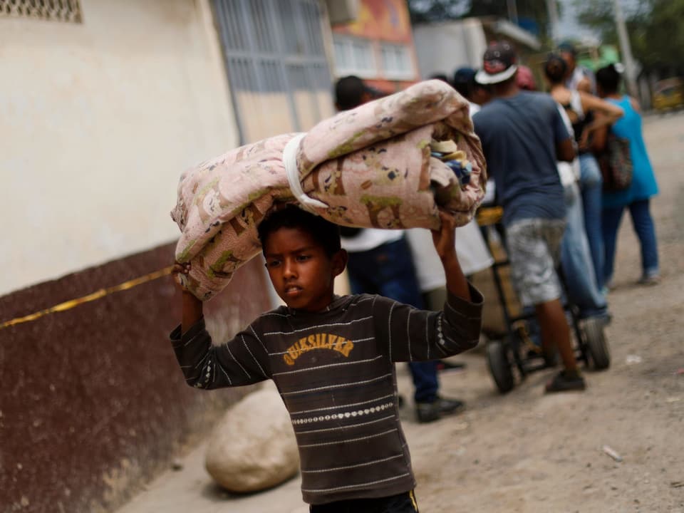 Ein venezuelanischer Junge trägt eine Matratze über seinem Kopf in einem Vorort von Cúcuta.