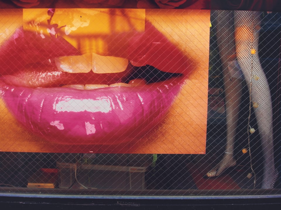 Plakat mit Lippen und eine Schaufensterpuppe daneben.