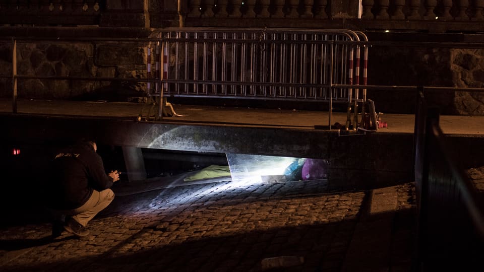 Ein Mitarbeiter der Stadt schaut in einen Schacht, um zu schauen,ob darin ein Obdachloser schläft.
