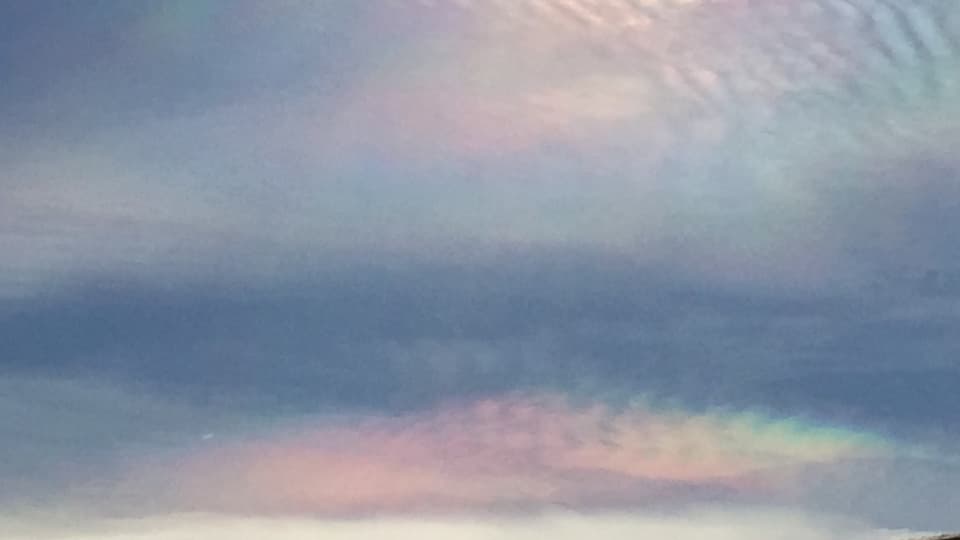Perlmutfarbene Wolken neben der Sonne.
