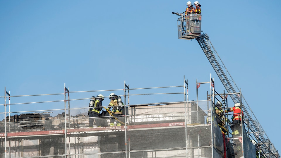Feuerwehrmänner auf einem Dach. Drehleiter mit Korb.