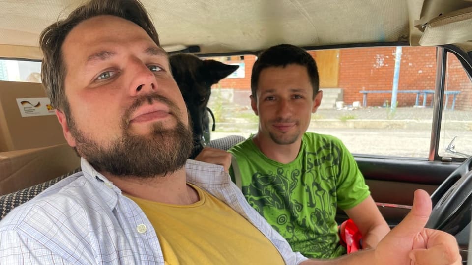 Denis und Pavel sitzen in einem Auto. 