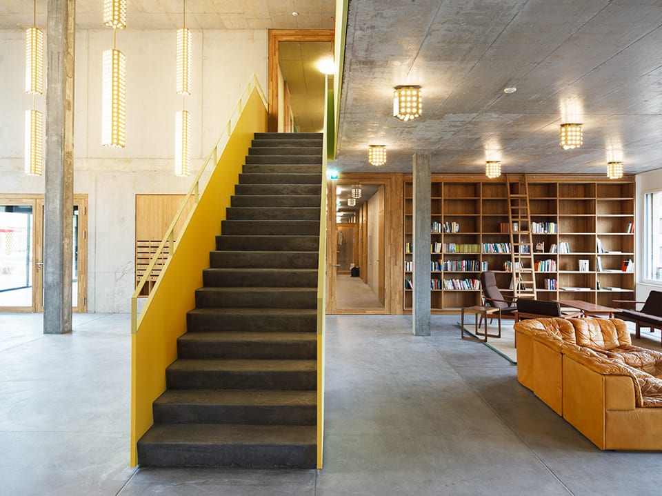 Grosse Betonhalle mit Treppe und Büchergestell.