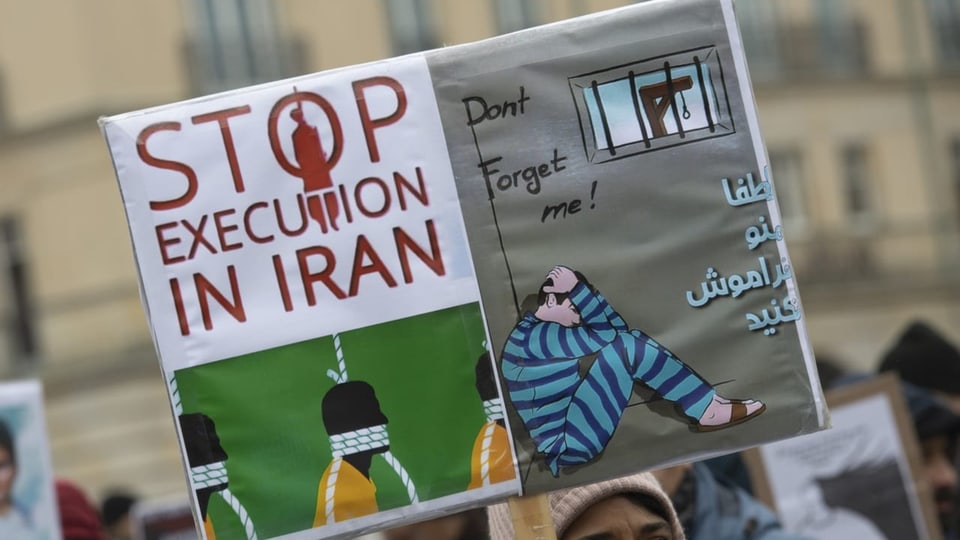 Frau hält Plakat. Darauf steht: Stop execution in Iran.
