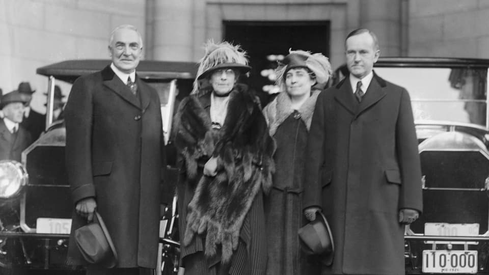 Warren G. Harding (links) und Vizepräsident Calvin Coolidge mit ihren Frauen – und den Autos mit denen sie gleich die Strecke zum Weissen Haus gefahren werden. 