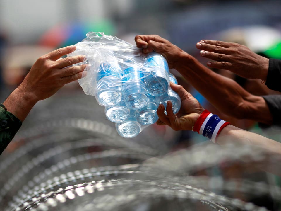 Ein Soldat gibt Demonstranten Wasserflaschen.