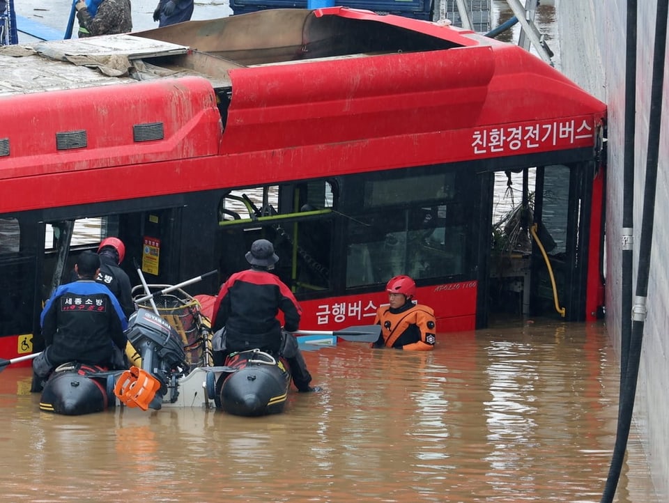 Menschen retten Passagiere eines Busses.